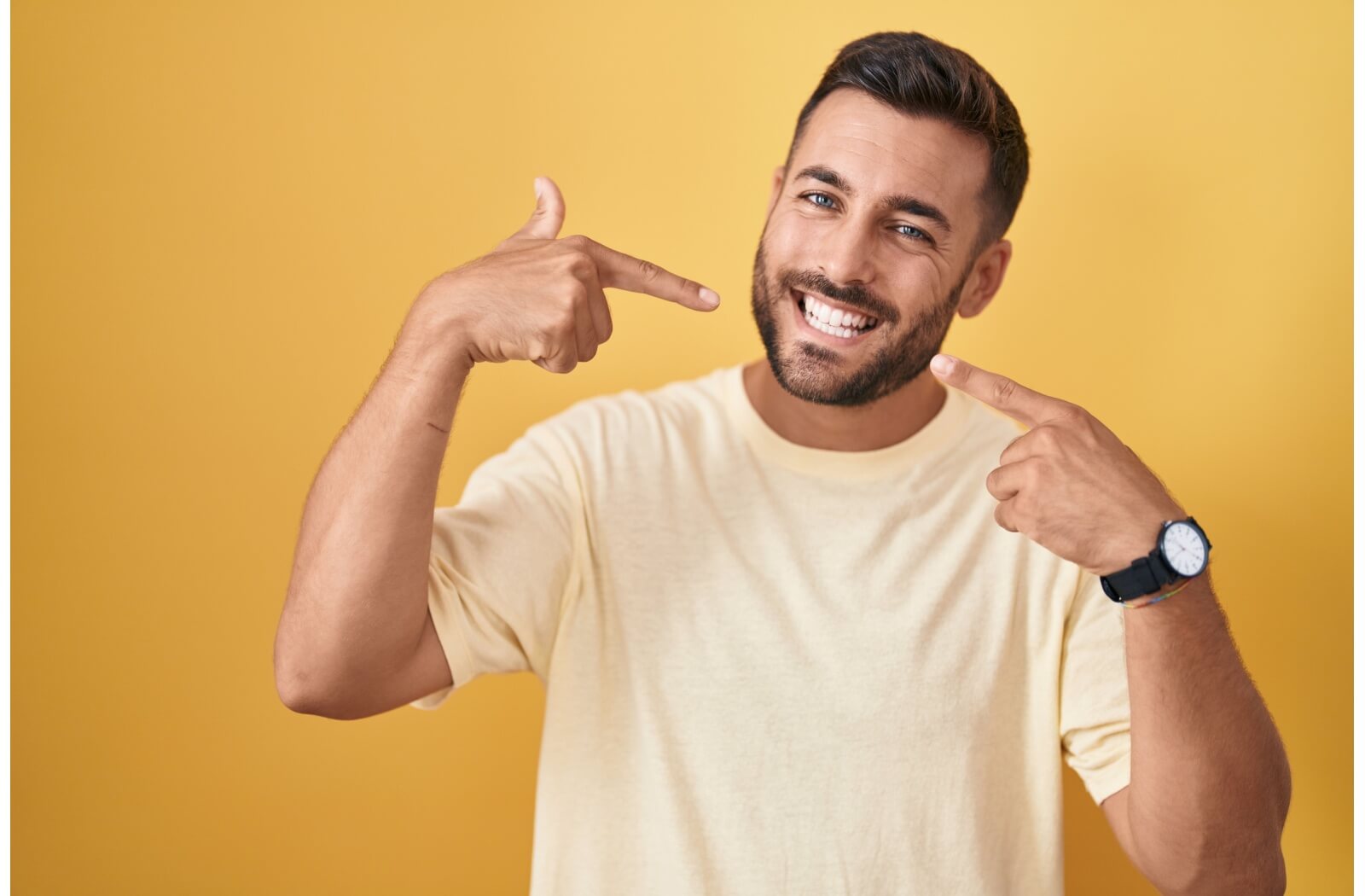 Someone points to their new, white smile, thanks to tooth bonding.