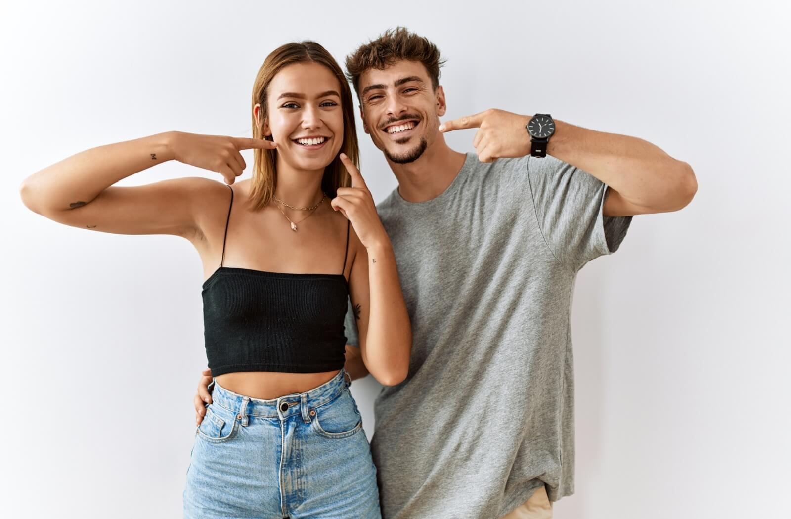 two people pointing at their healthy smile